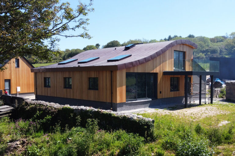 Finished building, timber clad with copper 'wave' roof.